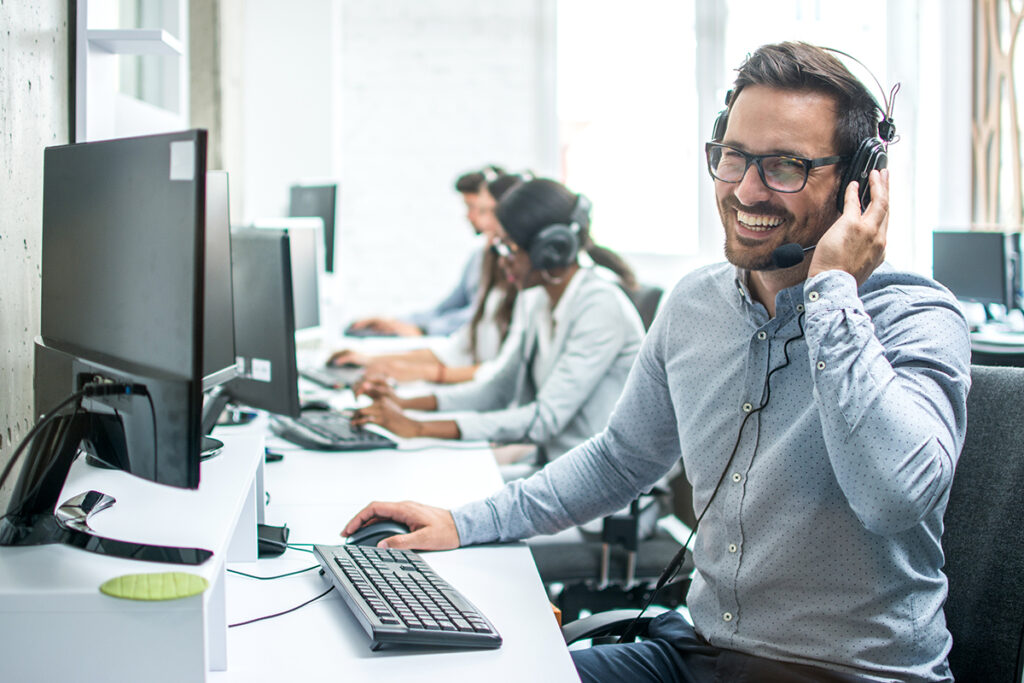Smiling handsome customer support operator with headset working in call center