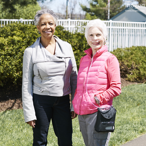 Woman with Inogen One portable oxygen concentrator standing and smiling with friend