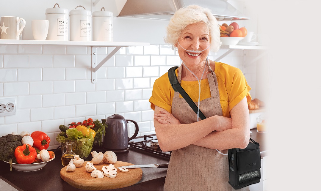 woman with inogen one portable oxygen concentrator standing in kitchen