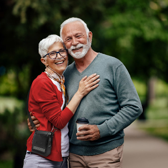 Man embracing woman with an Inogen portable oxygen concentrator in a park