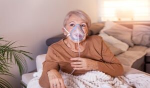 woman on couch using a portable oxygen mask