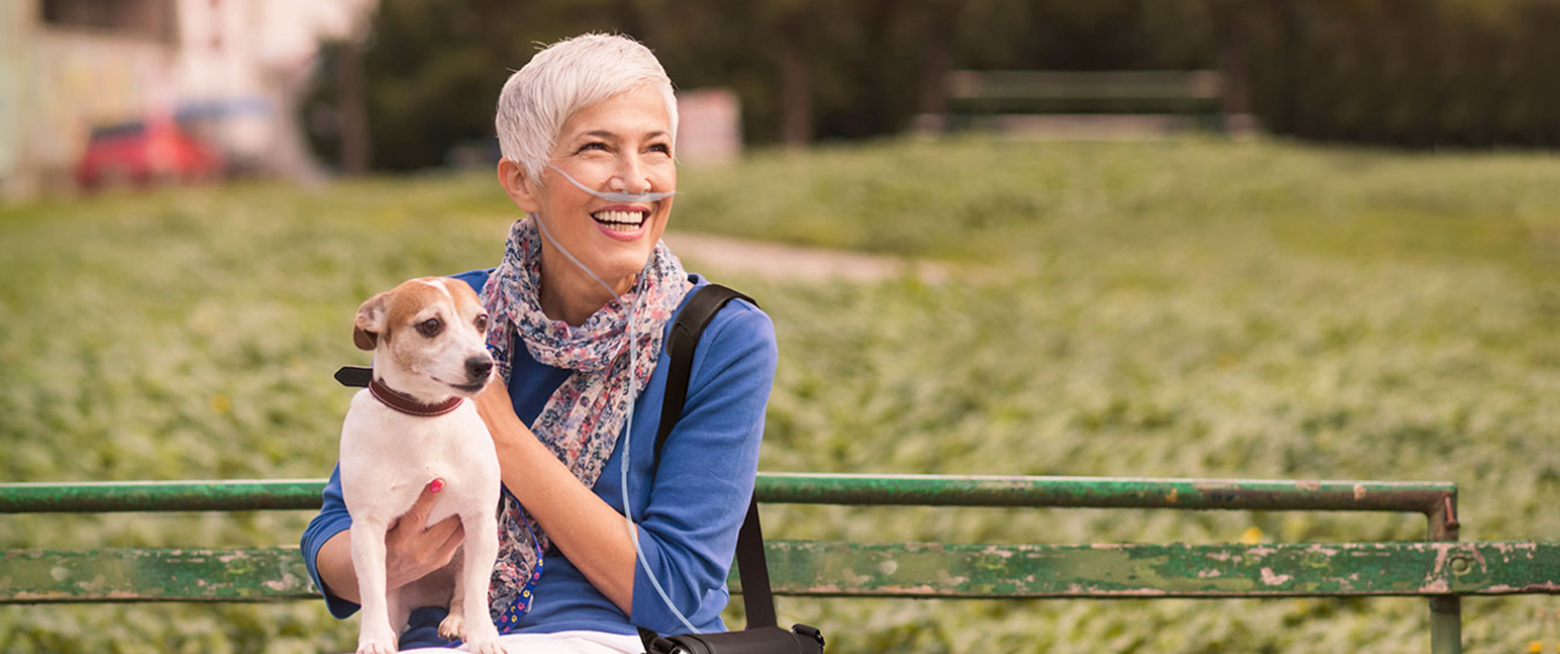 Woman and dog on a park bench with an Inogen Portable Oxygen Concentrator