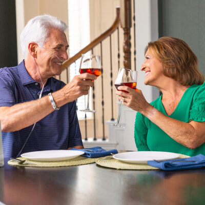 A man utilizing an Inogen Portable Oxygen concentrator while enjoying a glass of wine with a woman