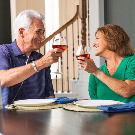 A man utilizing an Inogen Portable Oxygen concentrator while enjoying a glass of wine with a woman